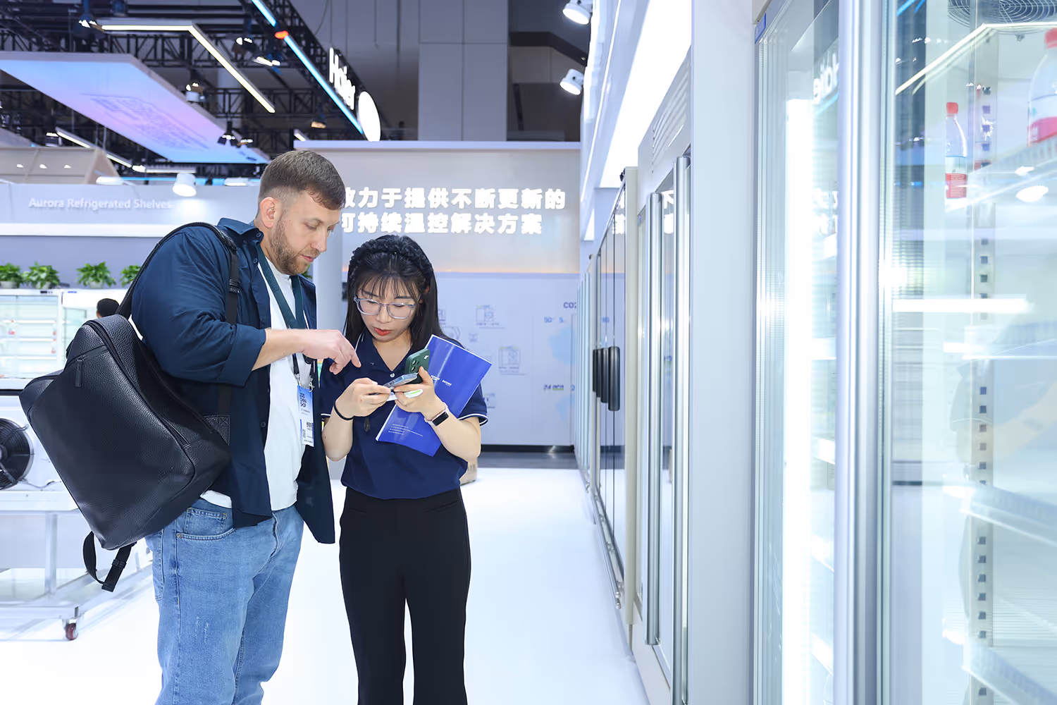 Group of business professionals in conversation at a trade show booth with signage in Chinese.