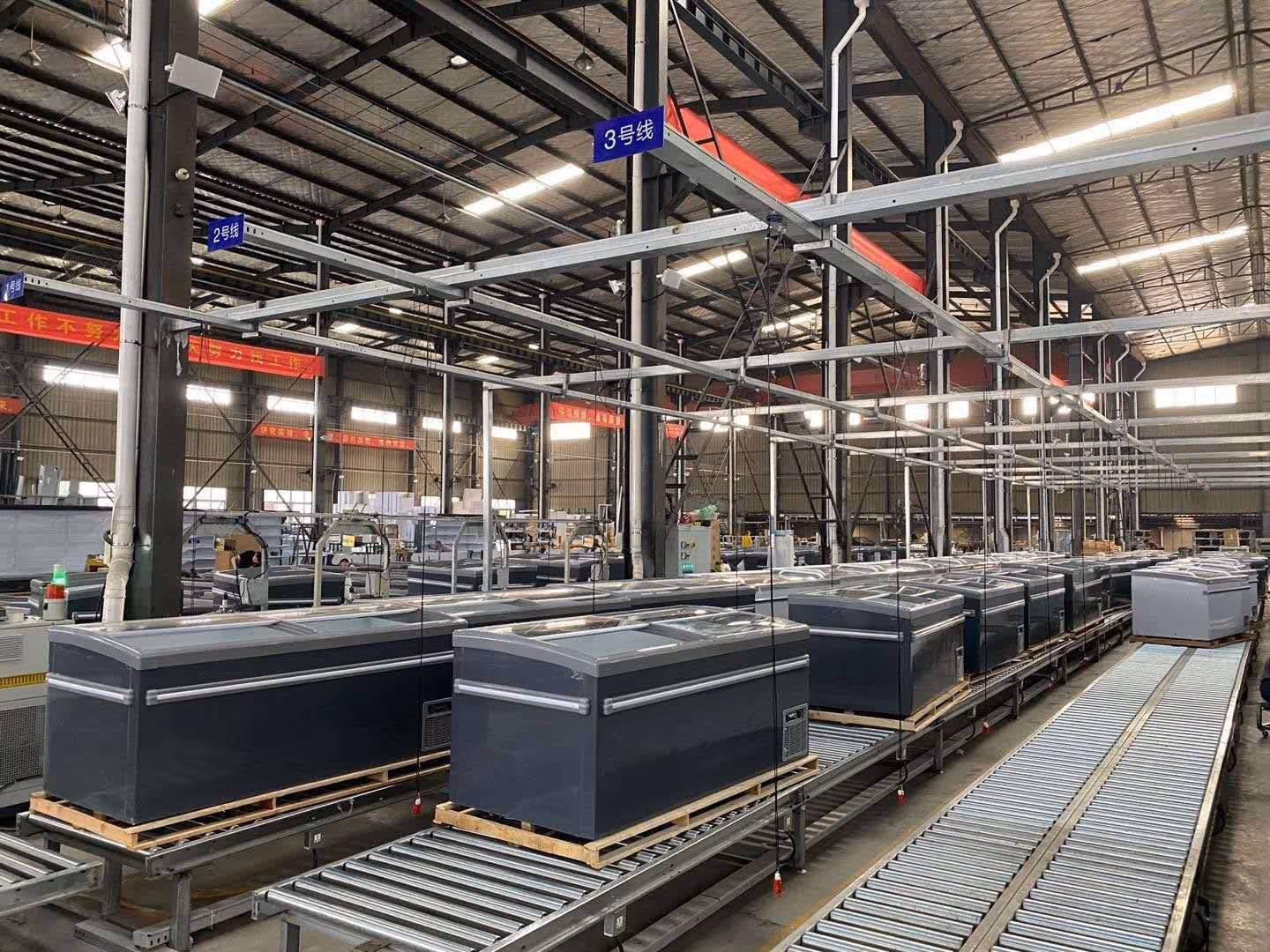 Industrial warehouse with conveyor belts transporting large freezer units.